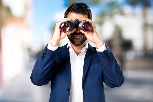 Hombre guapo con prismáticos sobre fondo desenfocado — Foto de Stock