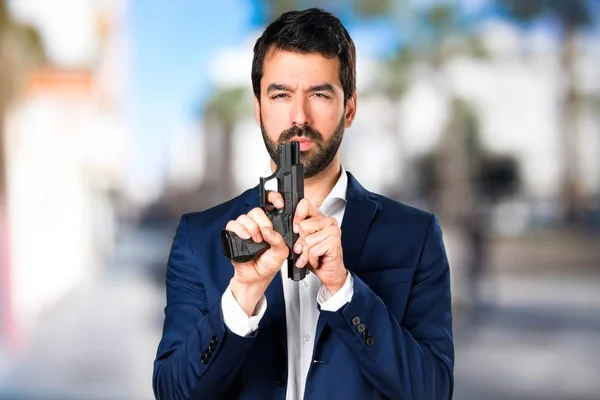 Handsome man holding a pistol on unfocused background — Stock Photo, Image