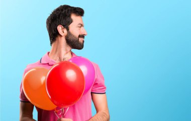 Balonlar tutarak ve renkli arka plan üzerinde yanal seyir yakışıklı delikanlı