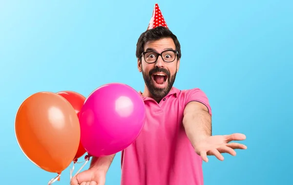 Handsome young man holding balloons on colorful background