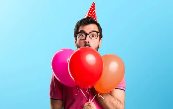 Bonito jovem segurando balões no fundo colorido — Fotografia de Stock
