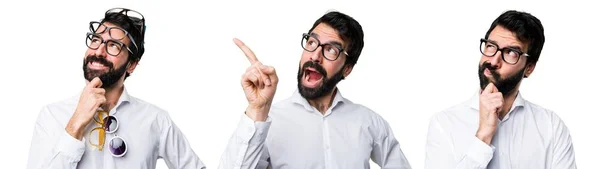 Hombre guapo con gafas apuntando hacia arriba y pensando —  Fotos de Stock