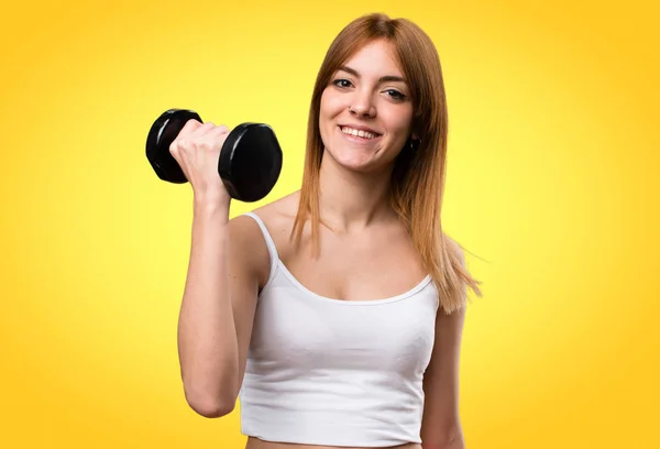 Hermosa mujer del deporte con mancuernas sobre fondo colorido — Foto de Stock