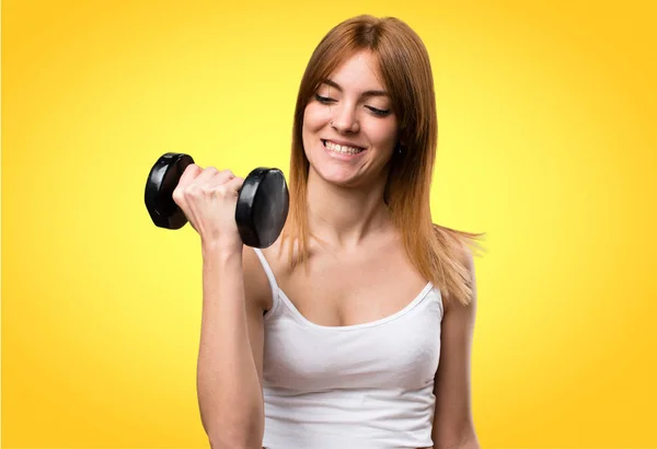 Hermosa mujer del deporte con mancuernas sobre fondo colorido — Foto de Stock