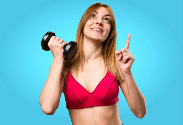 Hermosa mujer del deporte con mancuernas apuntando hacia arriba en bac colorido —  Fotos de Stock