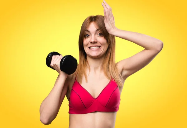 Bella donna sportiva con manubri che hanno dubbi sul colorato b — Foto Stock