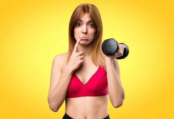 Triste hermosa mujer del deporte con mancuernas sobre fondo colorido —  Fotos de Stock