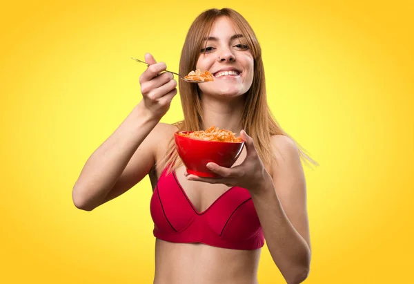 Jeune femme sportive mangeant des céréales d'un bol sur fond coloré — Photo