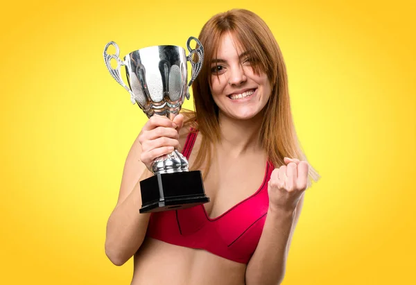 Młoda kobieta trzyma trofeum na tle kolorowe sportu — Zdjęcie stockowe