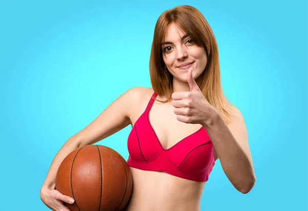 Mladý sportovní ženu s míčem basketbal na barevné pozadí — Stock fotografie