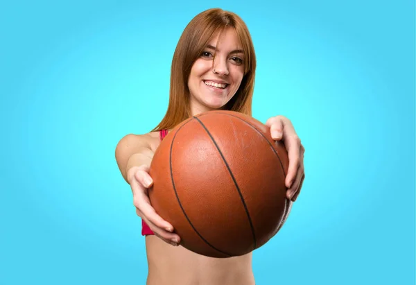 Jeune femme sportive avec balle de basket sur fond coloré — Photo