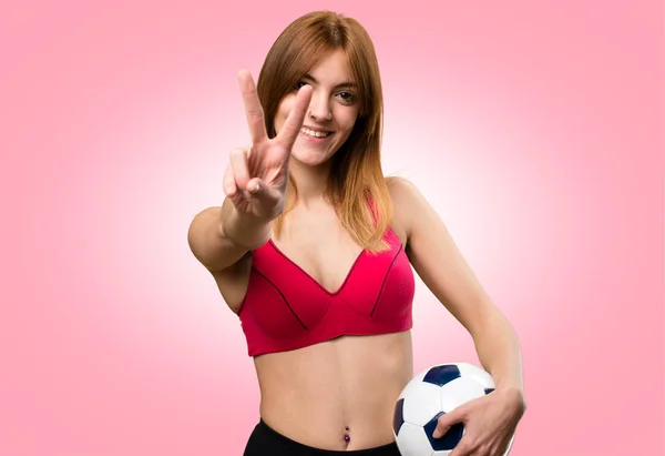 Jovem mulher esporte segurando uma bola de futebol no fundo colorido — Fotografia de Stock