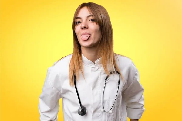 Młody lekarz kobieta co żart na kolorowe tło — Zdjęcie stockowe