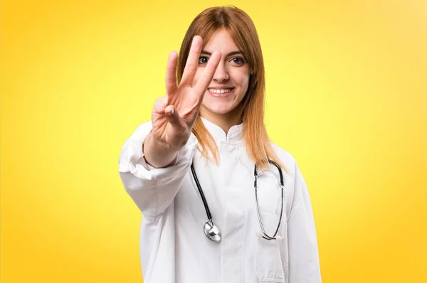 Jovem médico mulher contando três em fundo colorido — Fotografia de Stock
