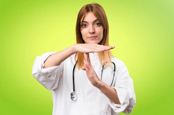 Молода лікарка робить жест часу на барвистому фоні — стокове фото