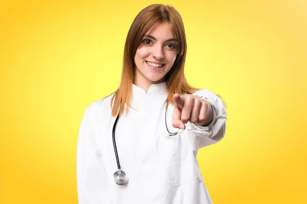Fiatal orvos nő, rámutatva, hogy az első színes háttérrel — Stock Fotó