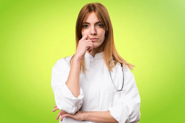 Jonge dokter vrouw denken over kleurrijke achtergrond — Stockfoto