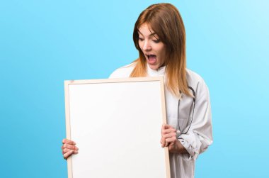 Boş bir afişini renkli arka plan üzerinde tutan kadın genç doktor