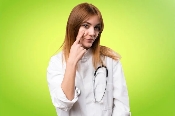 Fiatal orvos nő mutatja, valami színes háttérrel — Stock Fotó