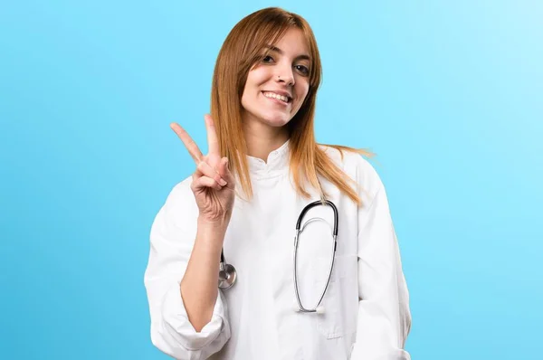 Jovem médico mulher fazendo gesto de vitória no fundo colorido — Fotografia de Stock