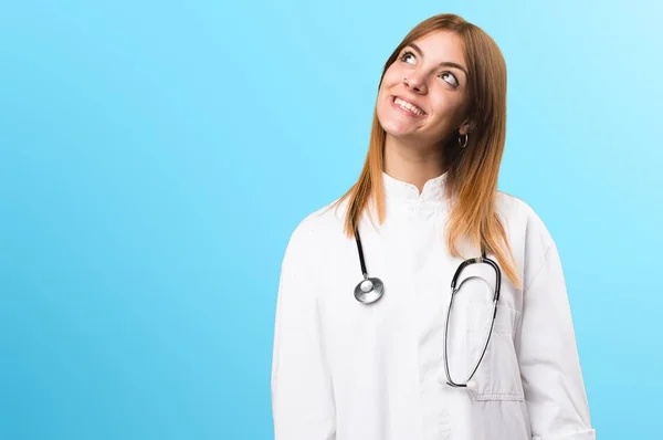 Fiatal orvos nő keresi fel a színes háttérrel — Stock Fotó