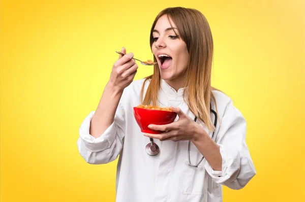 Молодая доктор женщина ест зерновые из миски на красочном фоне — стоковое фото