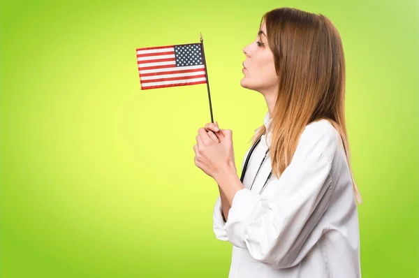 Молода лікарка тримає американський прапор на барвистому фоні — стокове фото