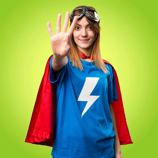 Gadis superhero cantik menghitung empat pada latar belakang berwarna-warni — Stok Foto