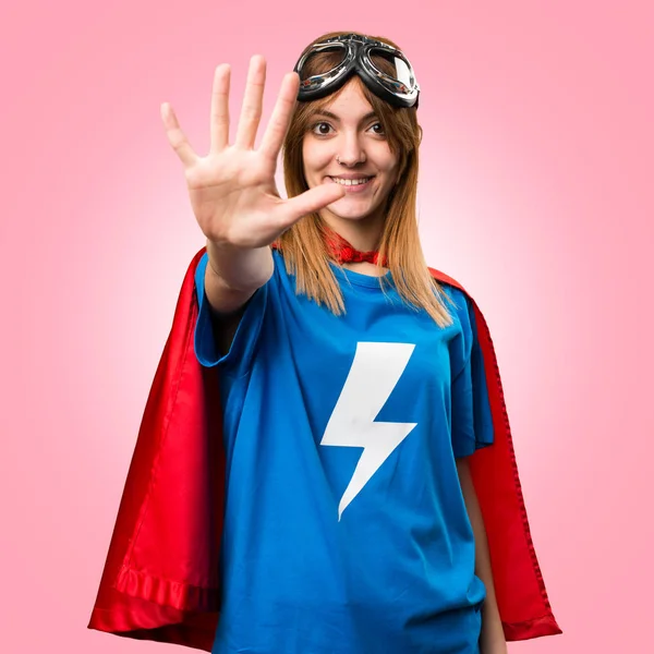 Pretty superhero girl counting five on colorful background