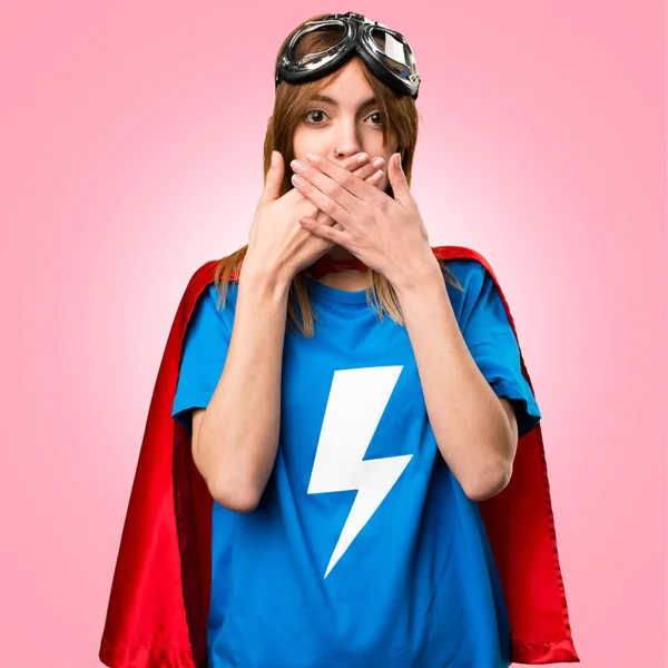 Pretty superhero girl covering her mouth on colorful background