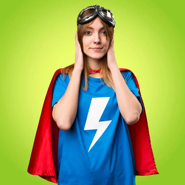 Pretty superhero girl covering her ears on colorful background — Stock Photo, Image