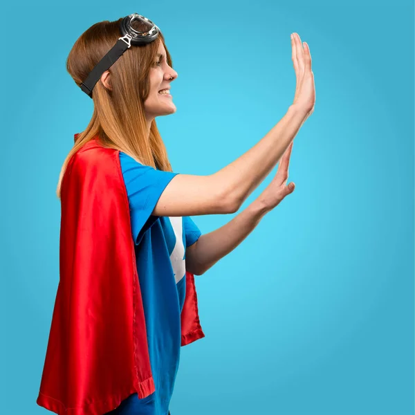 Pretty superhero girl pushing something on colorful background — Stock Photo, Image