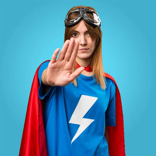 Довольно супергеройская девушка делает знак стоп на красочном фоне — стоковое фото