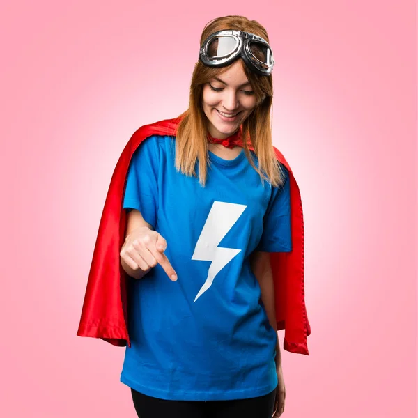 Dívka hezká superhrdina směřující dolů na barevné pozadí — Stock fotografie