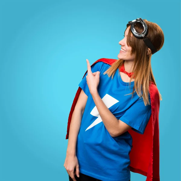 Dívka hezká superhrdina směřující zpět na barevné pozadí — Stock fotografie