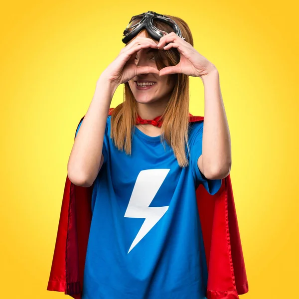 Mooie superheld meisje het maken van een hart met haar handen op kleurrijke — Stockfoto