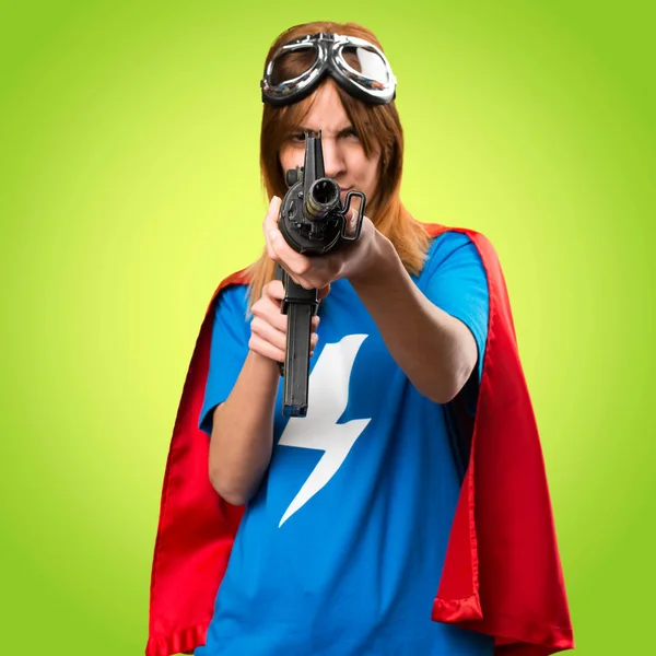 Pretty superhero girl holding a rifle on colorful background