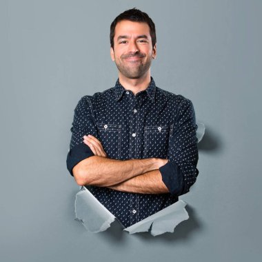 Esmer adam kollarını ile bir kağıt delikten geçti