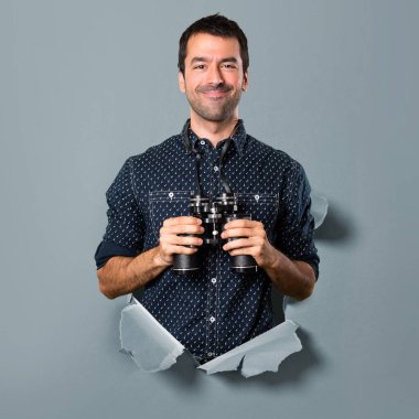 Bir kağıt delikten dürbünlü mutlu esmer adam