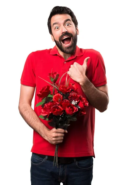 Hombre guapo sosteniendo flores con el pulgar hacia arriba sobre fondo blanco —  Fotos de Stock