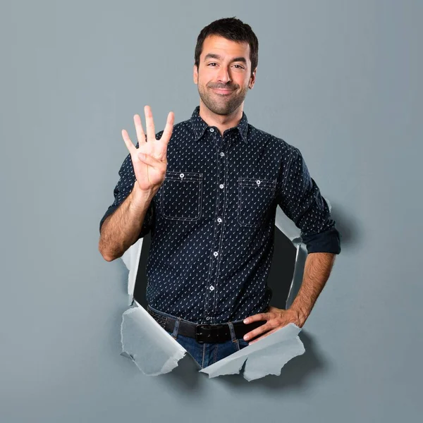 Morena hombre contando cuatro a través de un agujero de papel — Foto de Stock