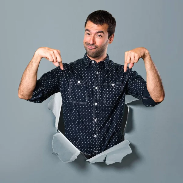 Brunette man pointing down through a paper hole