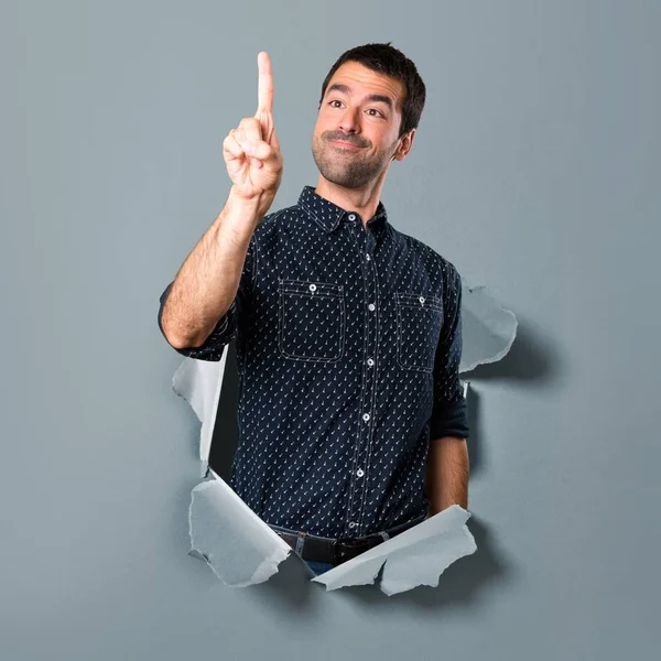 Morena hombre tocando en pantalla transparente a través de un agujero de papel —  Fotos de Stock