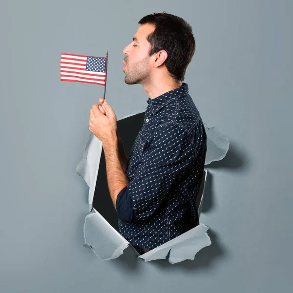 紙の穴を通してアメリカの国旗を持ってブルネットの男 — ストック写真