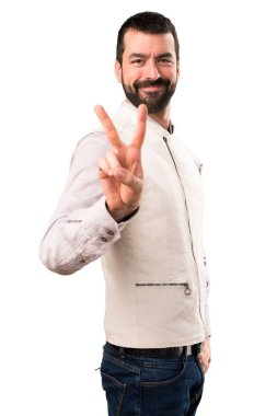 Beyaz arka plan üzerinde zafer jest yapma yelek ile yakışıklı adam izole