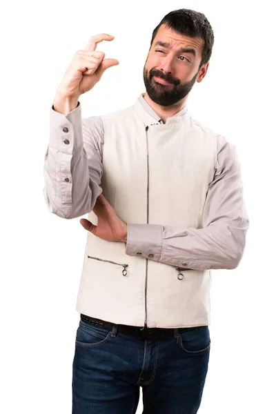 Красивий чоловік з жилетом робить крихітний знак на ізольованому білому тлі — стокове фото
