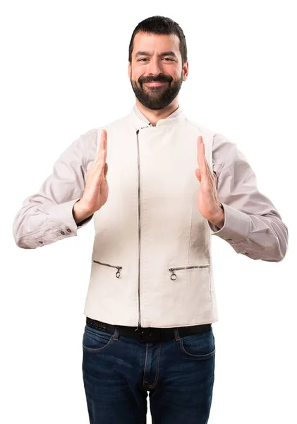 Bonito homem com colete segurando algo no fundo branco isolado — Fotografia de Stock