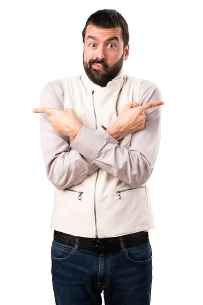 Handsome man with vest pointing to the laterals having doubts on isolated white background — Stock Photo, Image