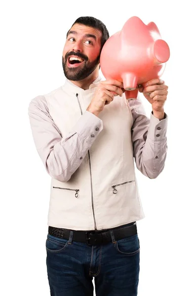 Jóképű férfi mellény gazdaság egy piggybank elszigetelt fehér background — Stock Fotó