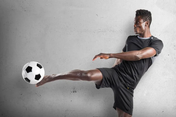 Uomo nero che gioca a calcio su sfondo strutturato — Foto Stock